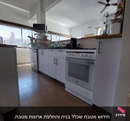 מטבח עם תנור לבן, ארונות וכלים על השיש